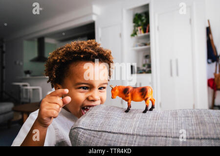 Happy cute boy playing with toy sur canapé à la maison Banque D'Images