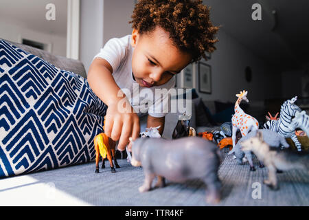 Low angle view of cute boy playing with toys, le canapé à la maison Banque D'Images