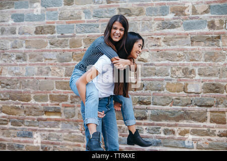 Happy woman usurpation de l'ami en position debout par wall Banque D'Images