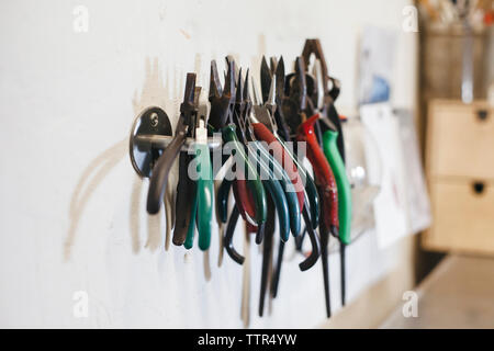 Close-up de pinces colorées hanging on rack par wall in workshop Banque D'Images