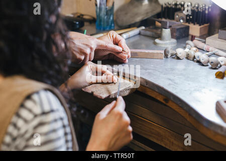 Les mains coupées de l'enseignement enseignant étudiant à l'anneau de forme sur la table à l'atelier Banque D'Images