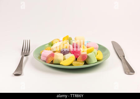 Couteau, fourchette et la plaque avec de la guimauve et gummy candies isolé sur fond blanc. Banque D'Images