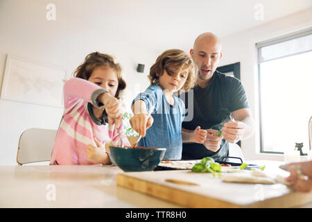 Père aider son fils et sa fille dans la préparation des aliments à la maison Banque D'Images