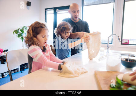 Père aider son fils et sa fille dans la préparation de pâte à table de cuisine Banque D'Images