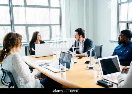 les gens d'affaires discutent tout en étant assis dans la salle du conseil au bureau Banque D'Images