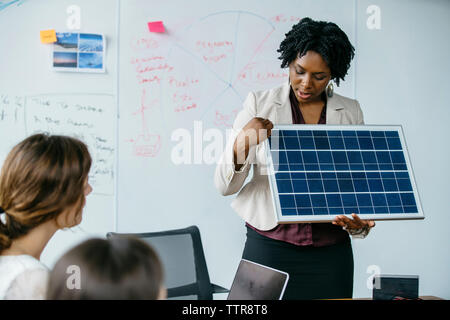 Businesswoman explaining panneau solaire modèle pendant meeting in office Banque D'Images