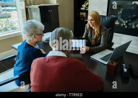 Portrait de conseiller financier montrant l'ordinateur tablette pour senior couple in office Banque D'Images