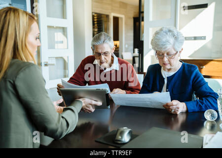 Senior couple lecture des documents au bureau du conseiller financier Banque D'Images