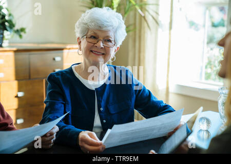 Senior woman looking away en maintenant dans les documents du bureau du conseiller financier Banque D'Images