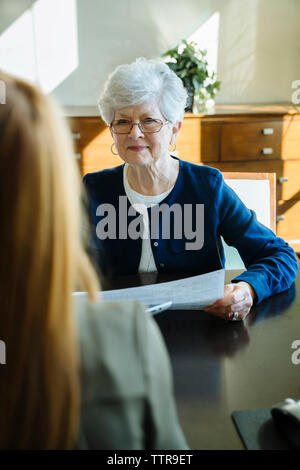 Senior woman holding documents tout en discutant avec conseiller financier à l'office de tourisme Banque D'Images