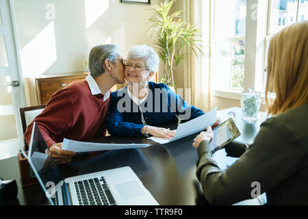 Man kissing woman tout en restant assis dans le bureau du conseiller financier Banque D'Images