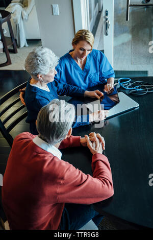 High angle view of senior couple et aide familiale assis à table à manger Banque D'Images