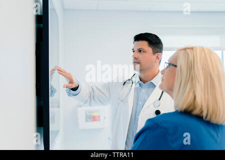 Médecin pointant sur écran tout en discutant avec des collègues à l'hôpital Banque D'Images
