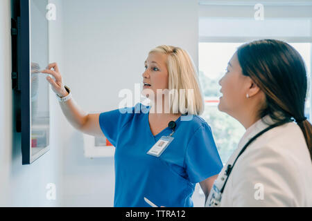 Femme médecin pointant à l'écran tout en discutant avec son collègue à l'hôpital Banque D'Images