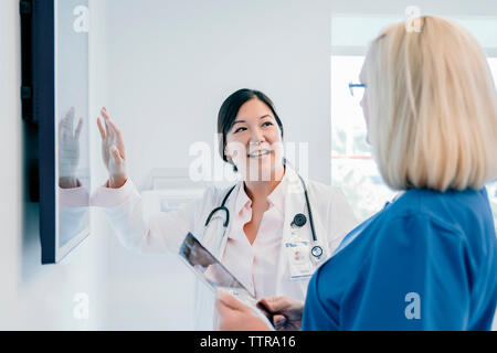 Médecin femme gesticulant à écran plat tout en discutant avec son collègue à l'hôpital Banque D'Images