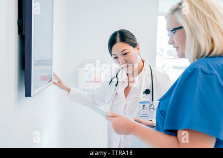Femme médecin montrant tablet computer à collègue tout en se tenant à l'hôpital Banque D'Images