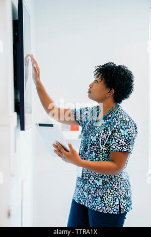 Femme médecin de toucher l'écran plat tout en maintenant à l'hôpital de l'ordinateur tablette Banque D'Images