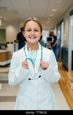 Portrait of Girl with stethoscope portant un sarrau debout in hospital corridor Banque D'Images