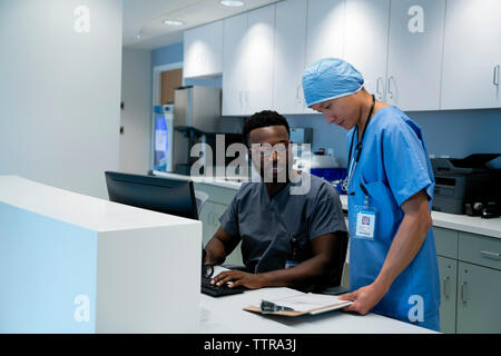 Médecin et chirurgien de l'examen medical chart sur presse-papiers à la réception de l'hôpital Banque D'Images
