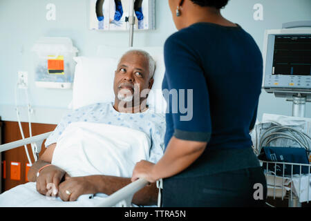 Le père à la fille, alors qu'en s'appuyant sur bed in hospital ward Banque D'Images