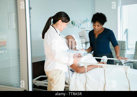 Femme médecin montrant tablet computer to senior patient in hospital ward et la femme Banque D'Images