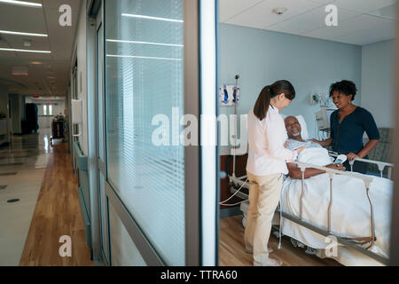 Female doctor talking with senior patient in hospital ward femme et vu à travers la porte Banque D'Images