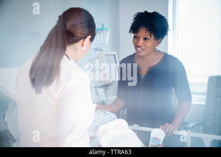 Fille de parler avec une femme médecin tout père lying on bed in hospital ward vu à travers la vitre Banque D'Images