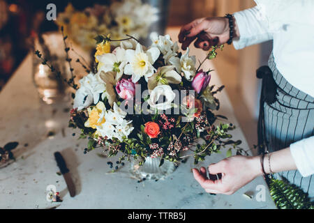 High angle portrait organisation fleuriste fleurs tout en se tenant à la table en magasin Banque D'Images