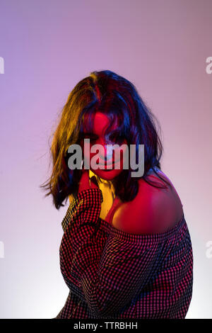 Side view of teenage girl wearing off robe en position assise contre fond violet Banque D'Images