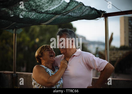 Heureux couple en se tenant sur le terrasse de l'immeuble pendant le coucher du soleil Banque D'Images