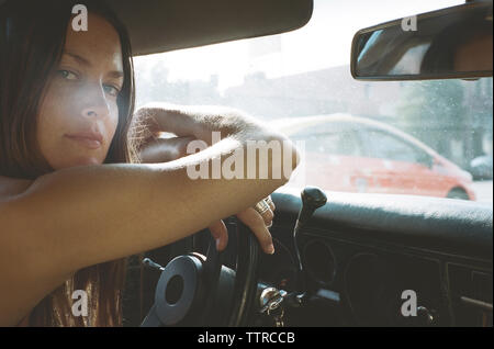 Portrait of young woman leaning on volant dans la voiture Banque D'Images