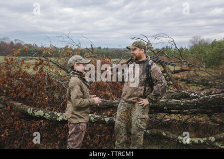 Père et fils en parlant de camouflage en se tenant sur le terrain Banque D'Images