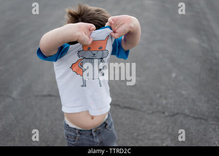 Portrait of boy dépose t-shirt en se tenant sur le trottoir Banque D'Images