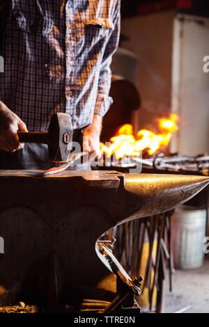 Portrait de l'artiste hammering metal sur à l'usine Banque D'Images