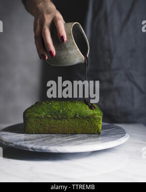 Portrait of woman pouring sur quatre-quarts au chocolat matcha Banque D'Images