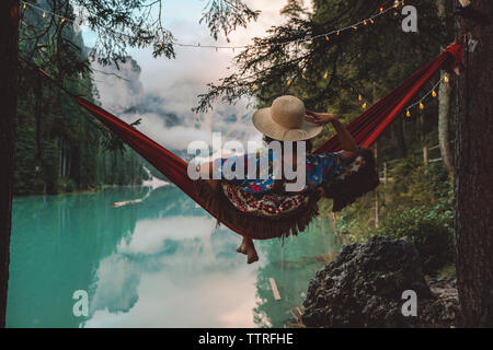 Young woman looking at view tout en restant assis dans un hamac sur le lac Banque D'Images