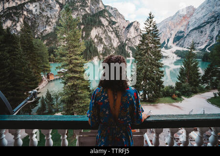 Young woman looking at view debout en balcon contre lac et montagne Banque D'Images