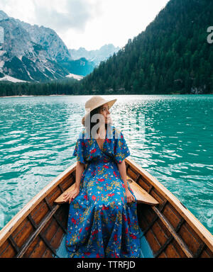 Young woman looking at view while sitting in boat on lake montagnes contre Banque D'Images