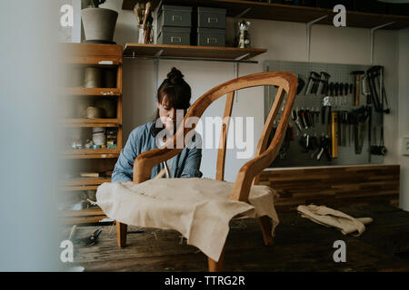 Rembourrage rembourreur femelle chaise en bois sur la table dans l'atelier Banque D'Images