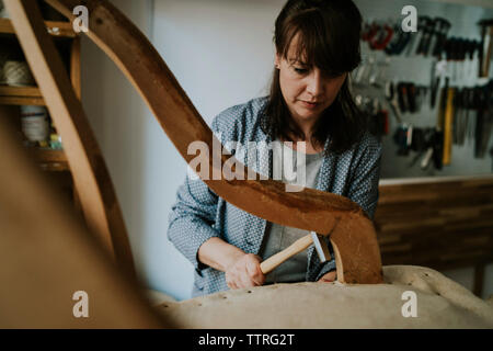 Confident female tapissier tapisserie chaise en bois dans l'atelier Banque D'Images