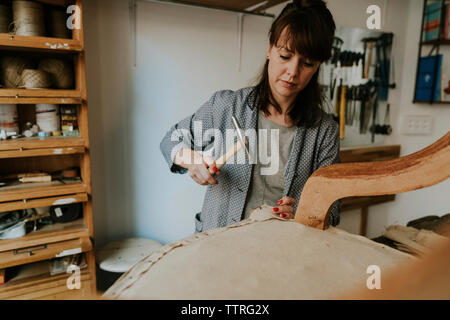 Confident female tapissier tapisserie chaise en bois debout dans l'atelier Banque D'Images