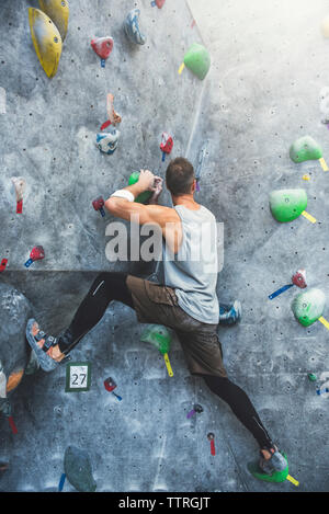 Toute la longueur de l'athlète au mur d'escalade au gymnase Banque D'Images