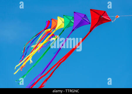 Une rangée de cerfs-volants colorés sur une seule ligne contre un ciel bleu clair. Banque D'Images