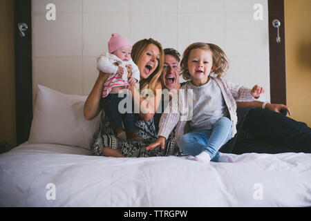 Les parents heureux avec leurs filles sur le lit chez lui Banque D'Images