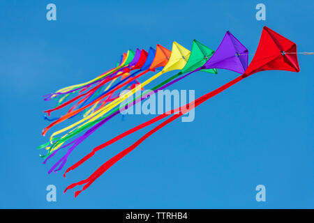 Une rangée de cerfs-volants colorés sur une seule ligne contre un ciel bleu clair. Banque D'Images