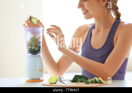 Girl putting Légumes et fruits à mixer électrique Banque D'Images