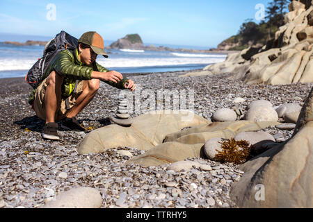 Pierres d'empilage adolescent sur mer at beach Banque D'Images