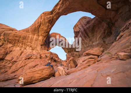 Low angle view of woman sitting on rock formation au Parc National Arches against sky Banque D'Images