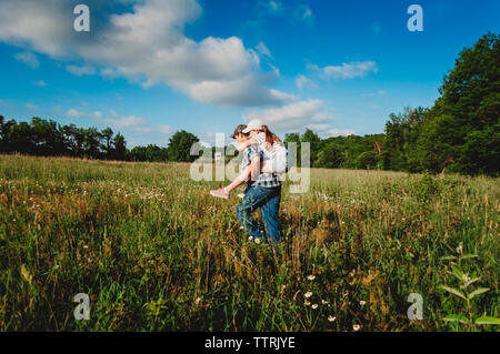 Vue latérale d'usurpation de frère soeur tout en marchant on grassy field at park Banque D'Images