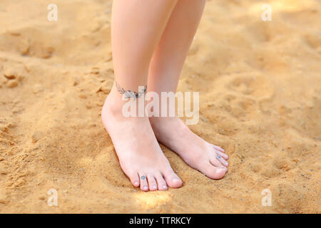 Les jambes des femmes avec des tatouages sur le sable Banque D'Images